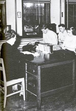 An old black and white photograph of a teacher and students in a classroom