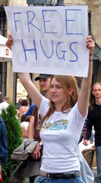 A girl holding a sign that says 'free hugs'