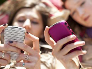 several young women holding their cell phones and texting