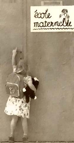 A little girl by a French sign for maternal school