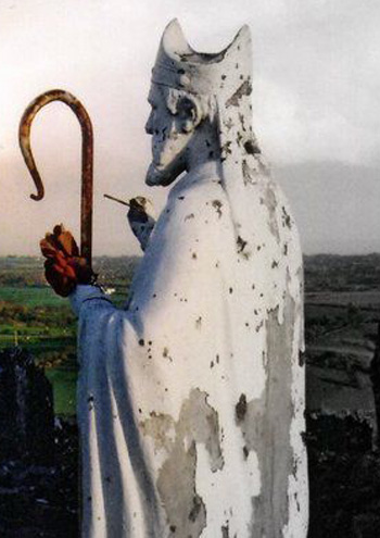 A statue of St. Patrick with his back to the setting sun