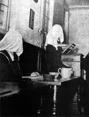 Black and White photograph of a Carmelite efrectory with two veiled nuns