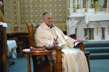 A priest sitting in a chair and 'presiding' over the mass
