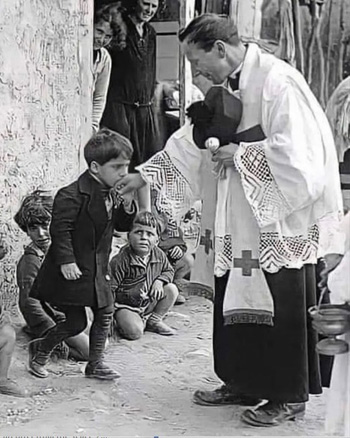 boy kisses hand of priest