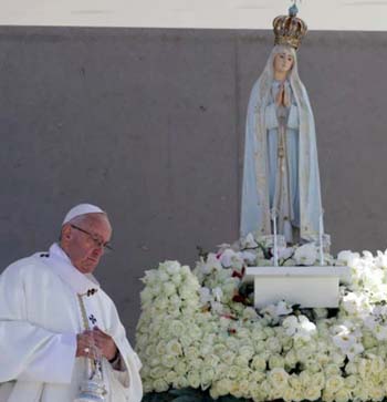 Pope Francis standing next to a statue of Our Lady of Fatima