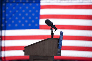 An empty podium and microphone in front of an American flag