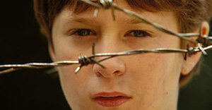 A boy behind barbed wire