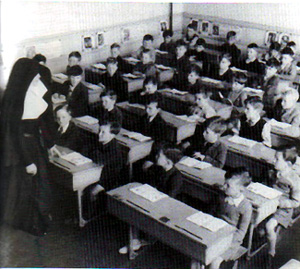 An old black and white photograph of a nun teaching in a classroom