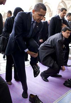 Obama taking off his shoes as he enters a mosque