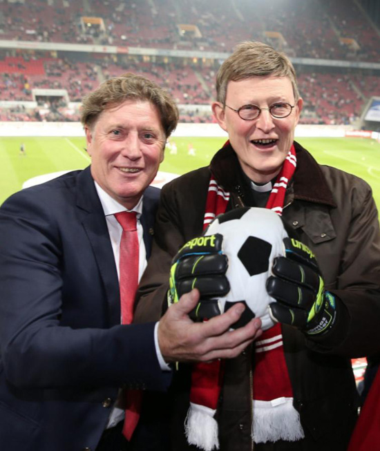 Cardinal Woelki holding a soccerball at a soccer stadium