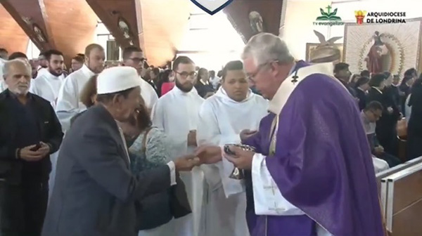 Archbishop Geremnias Steinmetz gives communion to Sheikh Mahairi