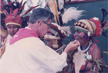 A priest gives communion to bare breasted native women