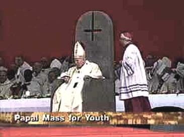 A news report on the Papal mass for Youth shows John Paul II on the throne of the inverted cross