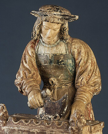 a wood carved statue of St. Crispin making shoes