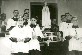 black and white photograph of altar boys with a procession statue of Our Lady and three doves at its base