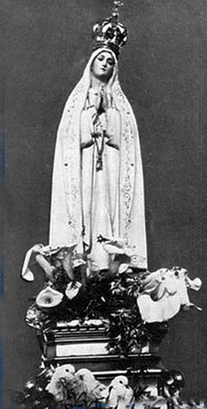 black and white photograph of a statue of Our Lady of Fatima with three doves at the base