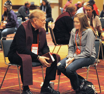 novus ordo confession with a priest and young woman penitent sitting in cheap chairs in an open auditorium at a world youth day