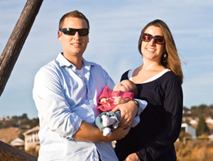 A young couple with sunglasses holding their baby