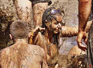 Young men and women splash around in mud at the Woodstock festival, Poland, July 31, 2009