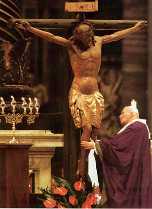 Pope John Paul II touching the legs of a crucifix