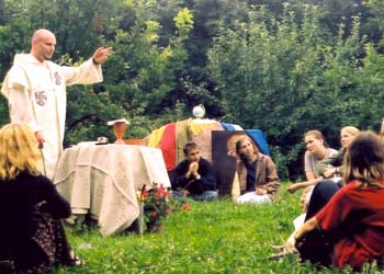 A priest says mass for youths seated on grass